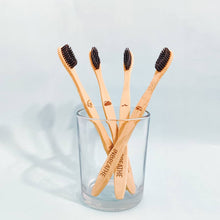Load image into Gallery viewer, Set of 4 biodegradable bamboo toothbrushes with activated charcoal bristles for natural oral care.
