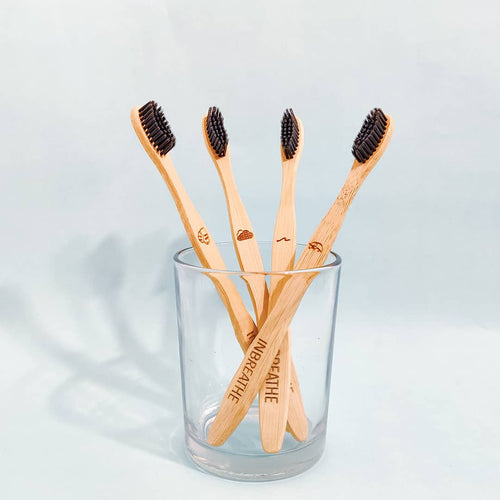 Set of 4 biodegradable bamboo toothbrushes with activated charcoal bristles for natural oral care.