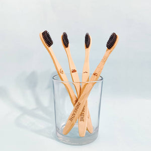 Set of 4 biodegradable bamboo toothbrushes with activated charcoal bristles for natural oral care.